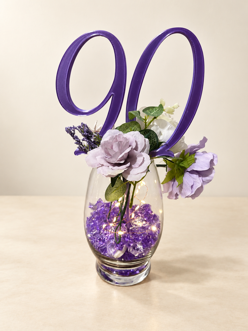 Purple number 90 centerpiece pick styled in a floral vase; vase and accessories are not included